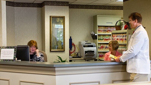 Dr. Clayton McCarl talking to team member at reception desk