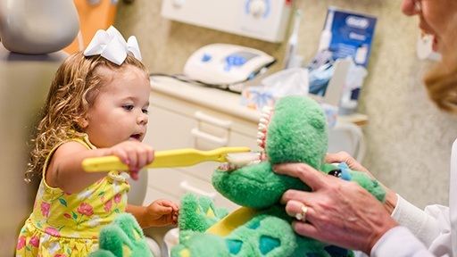 Little girl in dental chair learning tooth brushing