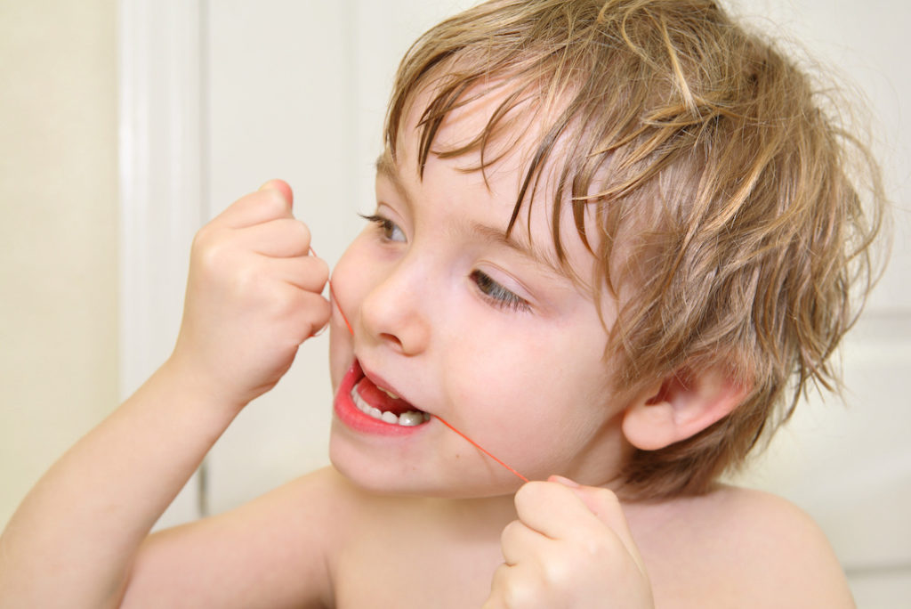Young boy flossing teeth