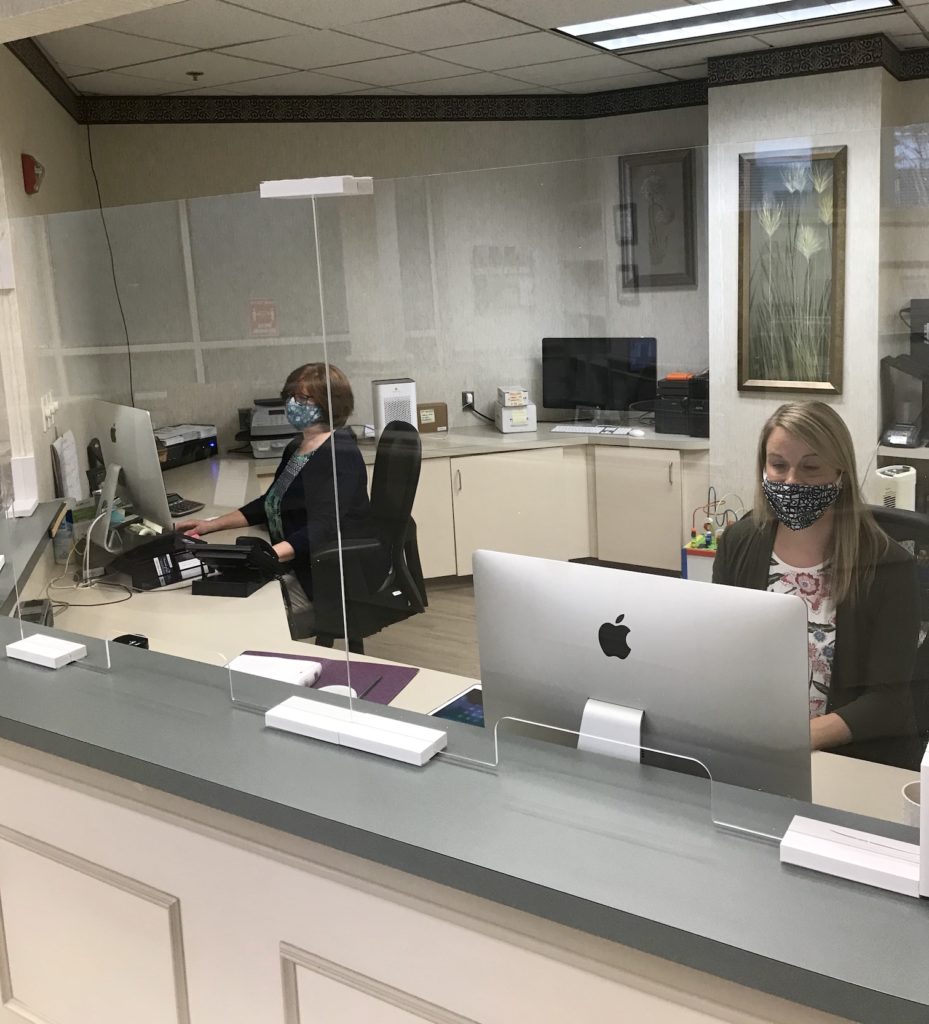 Two McCarl Dental Group team members behind dental office reception desk