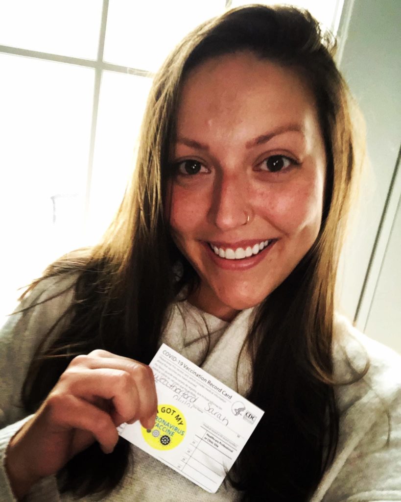 Dental team member holding up Covid vaccination form